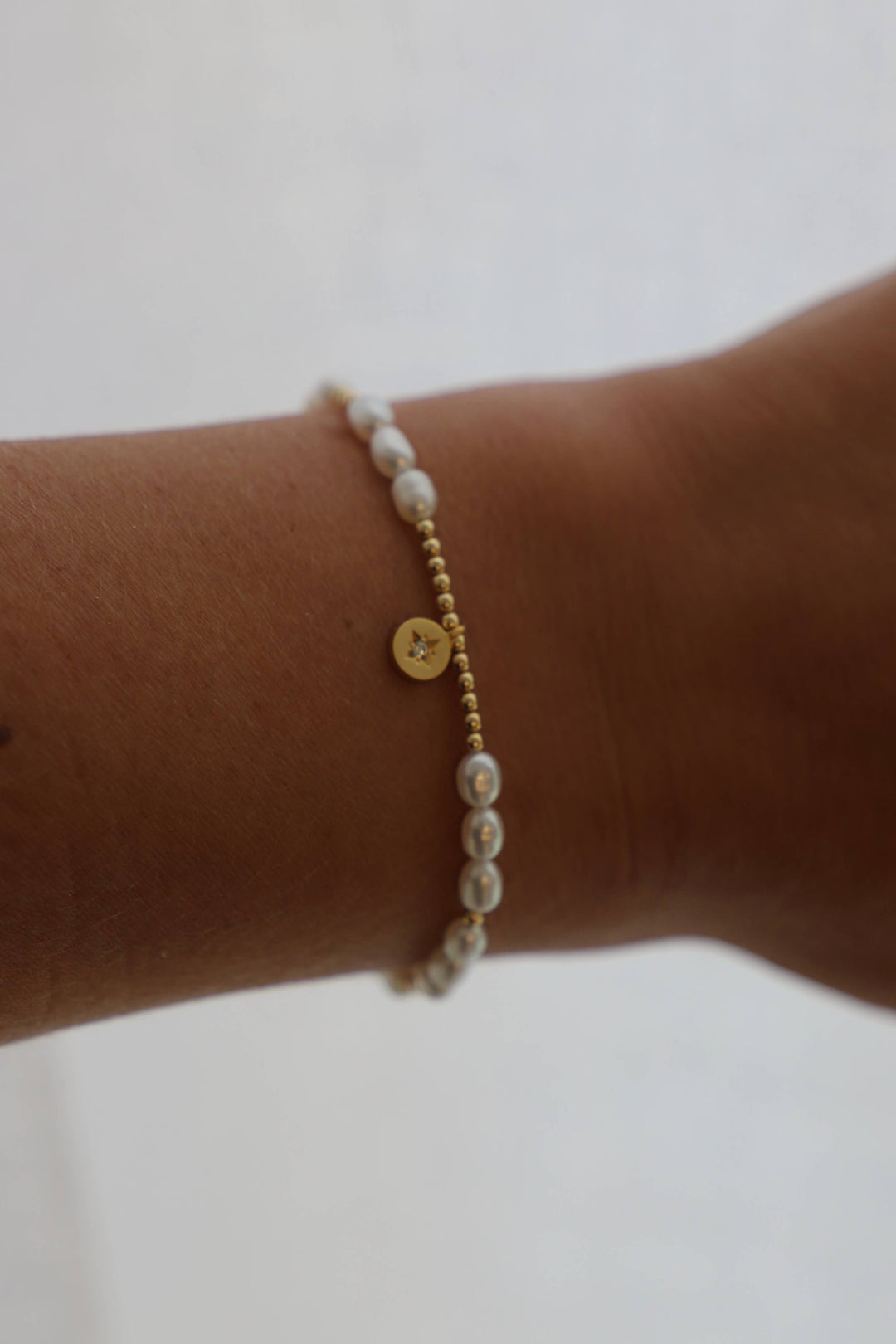 A bracelet featuring freshwater pearls and a gold plate star medallion with gold filled accent beads. Gift