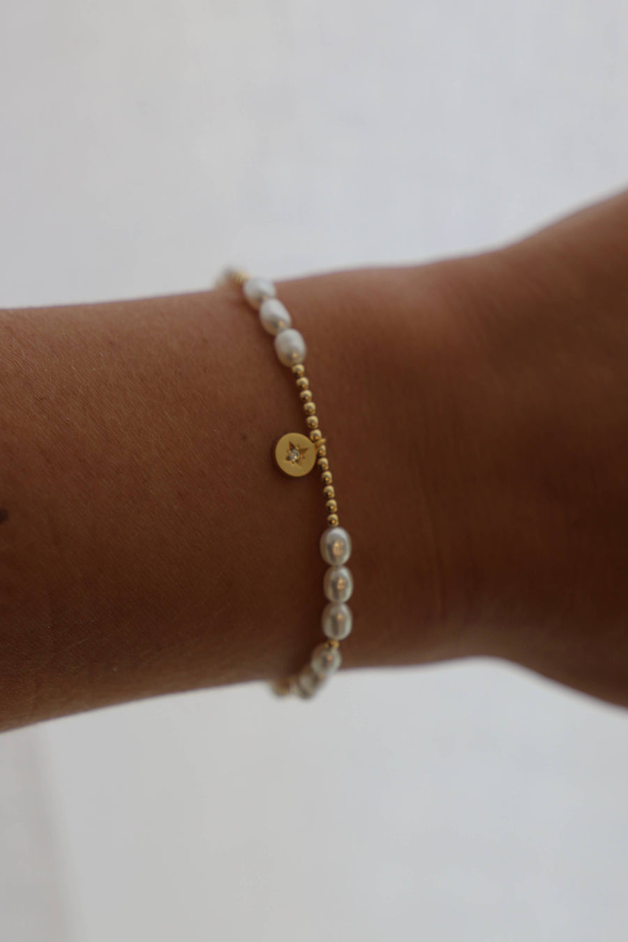 A bracelet featuring freshwater pearls and a gold plate star medallion with gold filled accent beads. Gift